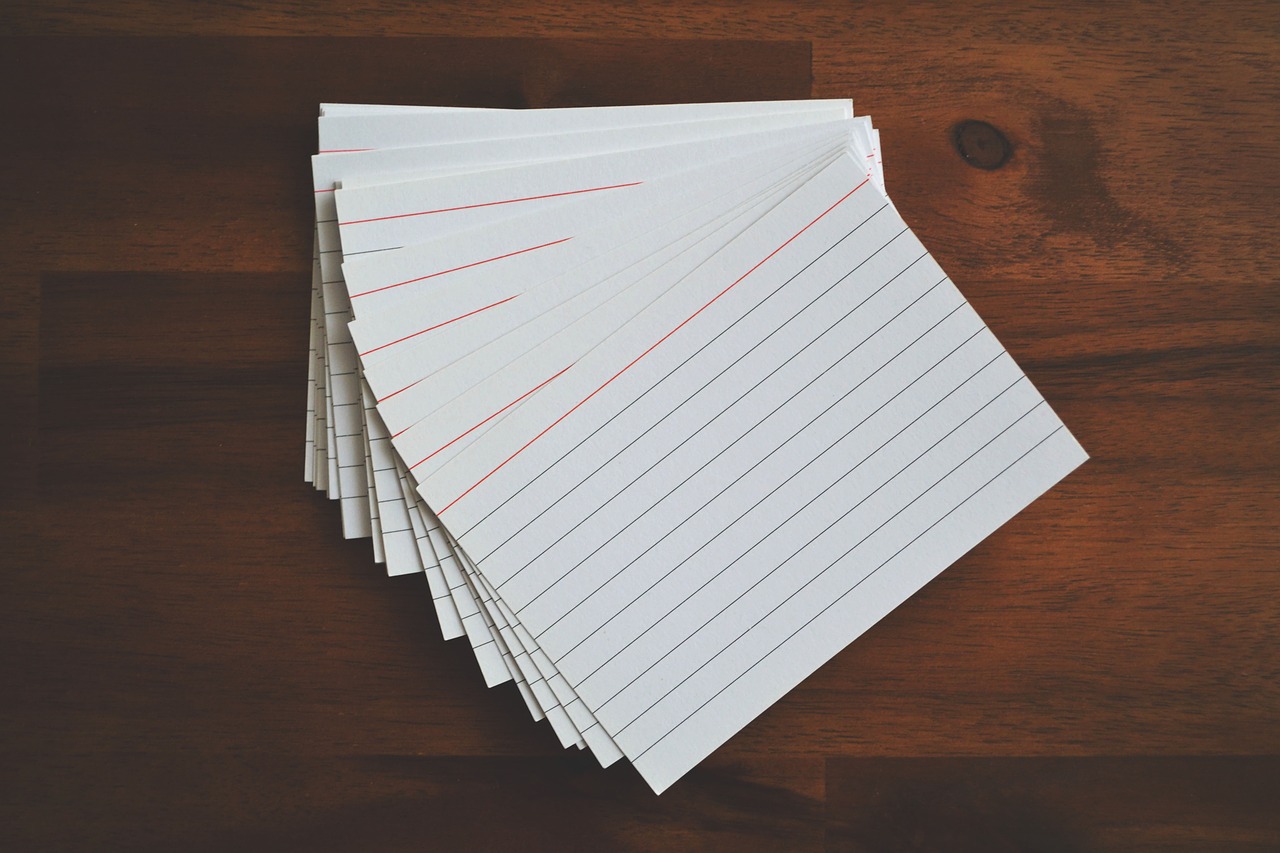 Photograph of a bunch of blank index cards laid in a fan shape on a wooden tabletop