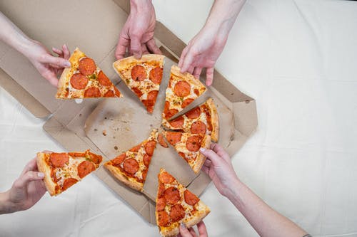Hands grabbing slices of pizza