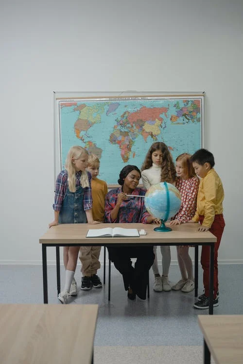 teaching point to globe surround by students